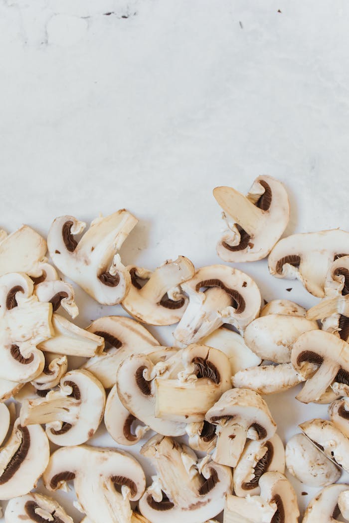 Top view of fresh sliced mushrooms on a clean white marble background, perfect for healthy eating concepts.