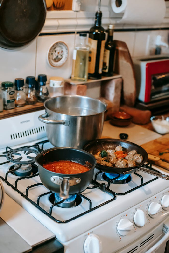 Cozy kitchen with cooking pans on a stove and spices in the background.