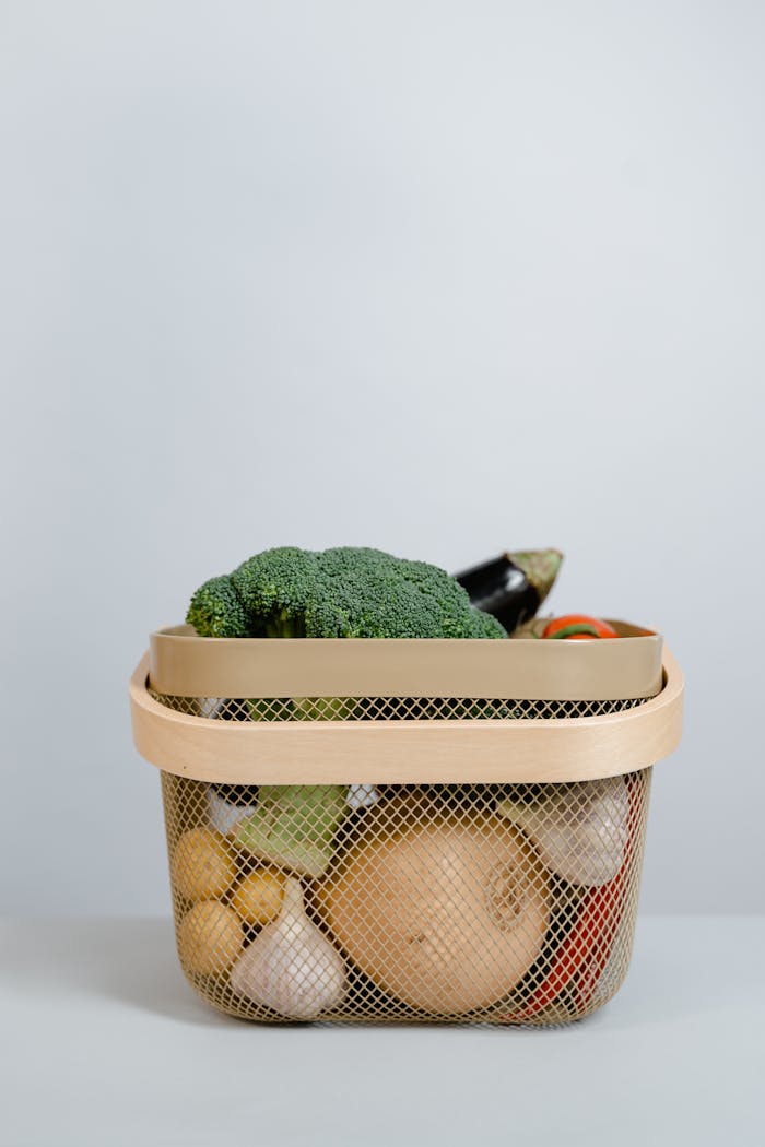 Basket filled with fresh organic vegetables against a light background, ideal for healthy living concepts.