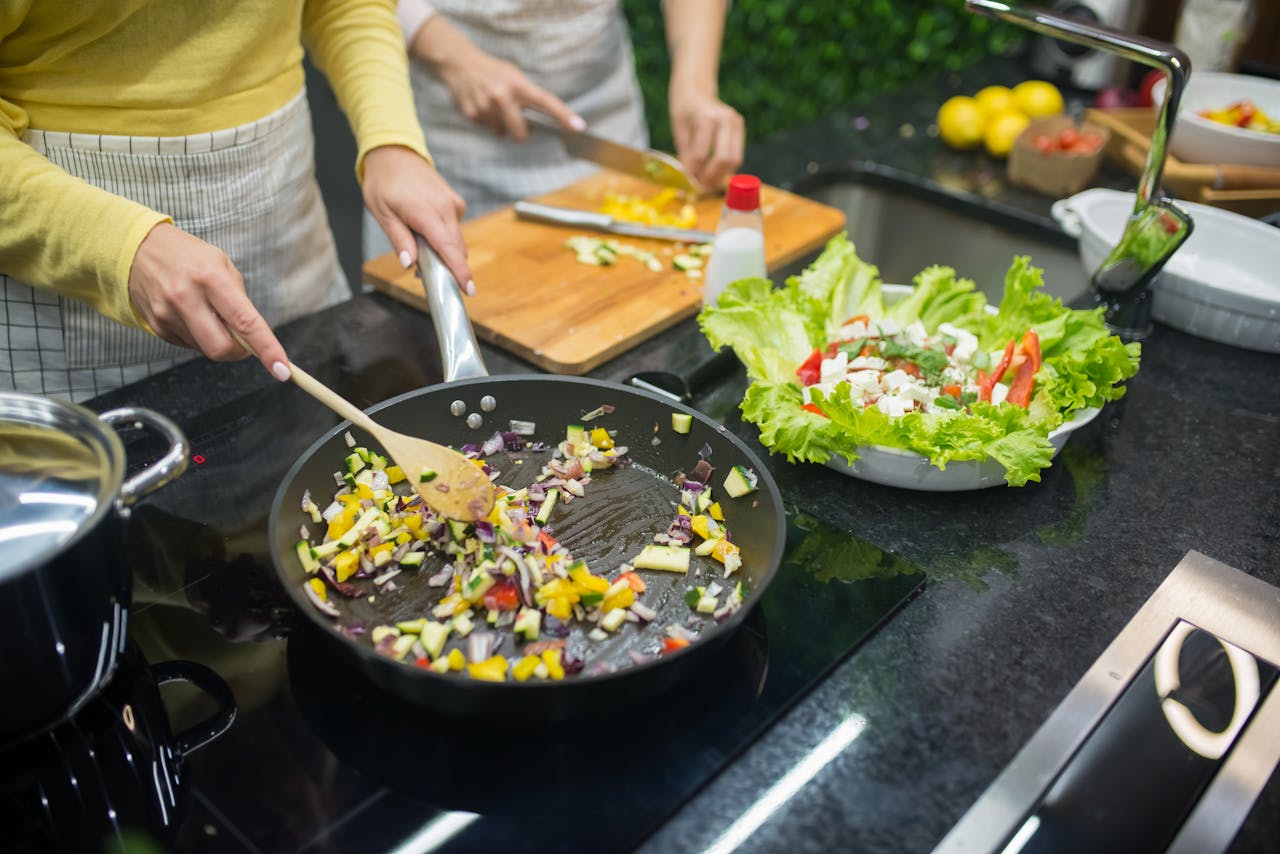 The Art of Drawing Readers In: Your attractive post title goes here Two adults cooking fresh vegetables on a stove, preparing a healthy meal in a modern kitchen.